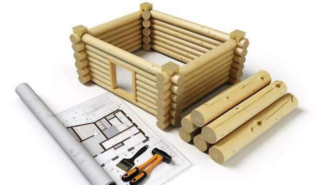 A wooden cabin model with logs, blueprints, and tools.