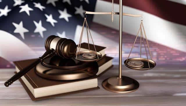 A gavel and scales on books, with a U.S. flag background.