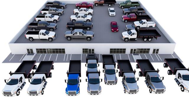 A mix of pickup trucks and flatbed trucks parked on a two-level parking structure.