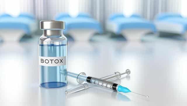 A vial labeled "Botox" with a syringe, on a medical table.