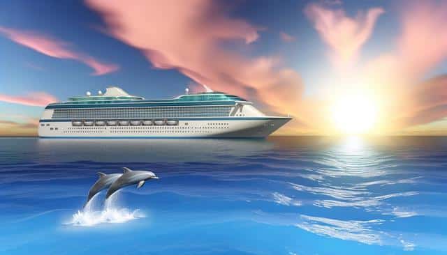 Cruise ship on ocean at sunset with two dolphins jumping.