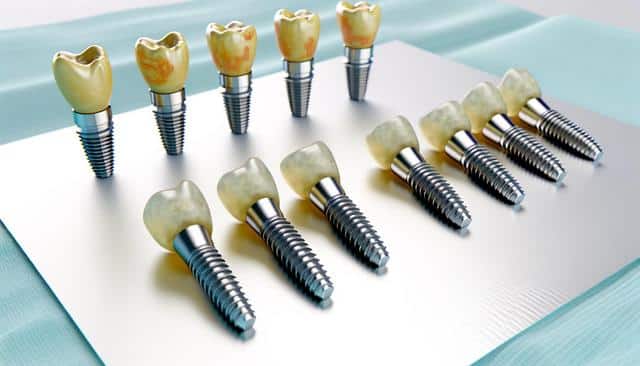 Dental implants with tooth-colored tops, displayed in two neat rows on a shiny surface.