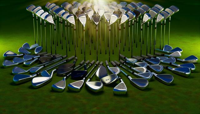 A set of golf clubs with colorful grips lies on the grass, with a golf course and bag in the background.