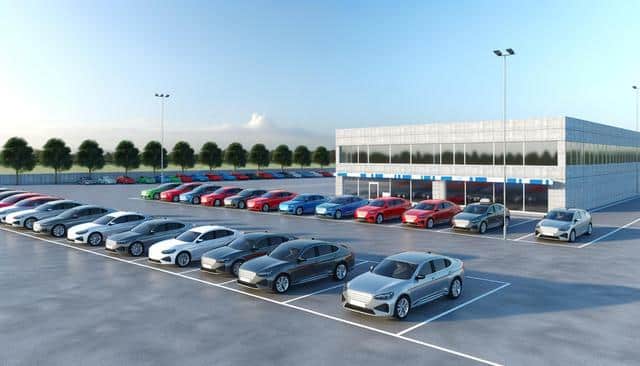 Parking lot with colorful cars and a modern building under a clear sky.