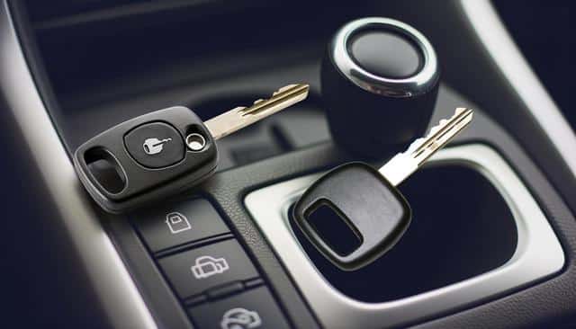 Two car keys placed on a car's center console next to a gear shift.