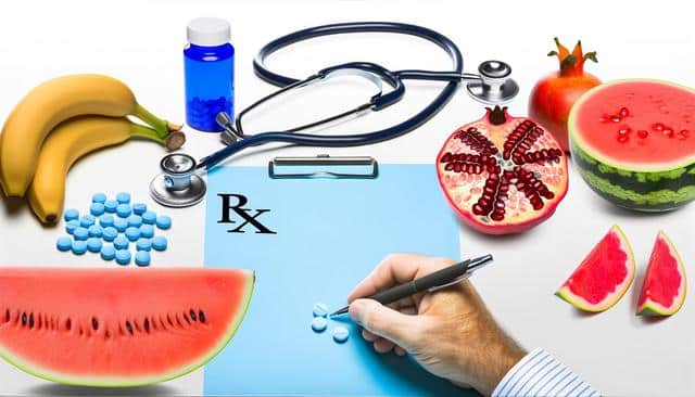 Fruits, stethoscope, pills, and a writing hand on a medical-themed background.