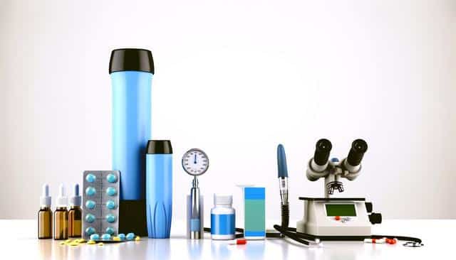 Medical and lab equipment, pills, and a microscope on a white surface.