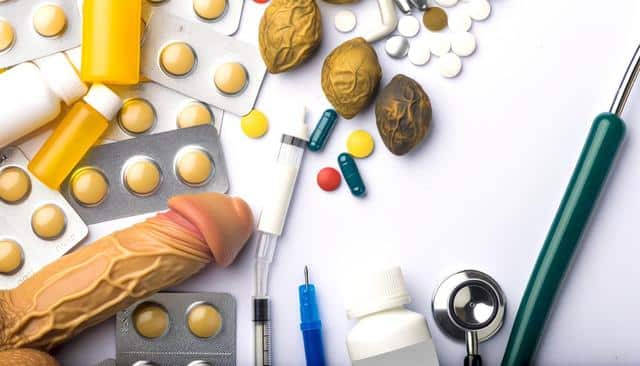 Various medications, a stethoscope, and a medical tool are arranged on a white surface.