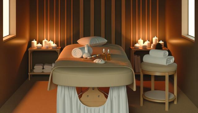 A cozy spa room with a massage table, candles, towels, and essential oils.