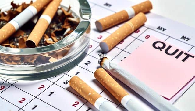 Cigarettes and ashtray on a calendar with a pink "QUIT" note.